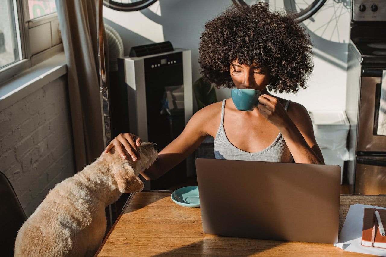 Ein Mensch sitzt mit seinem Hund gemütlich am Küchentisch, liest oder schreibt – ein Moment der Inspiration.