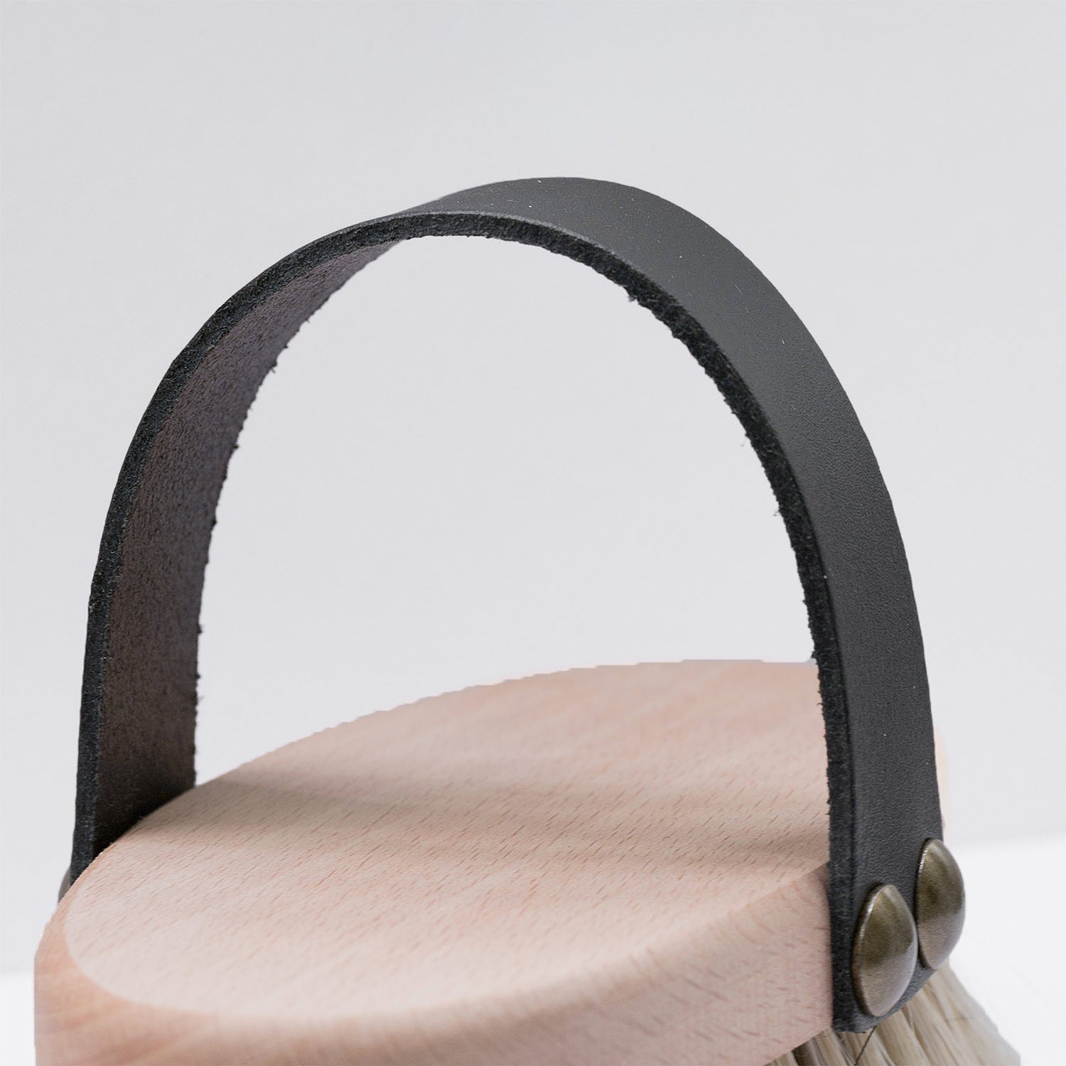 Hundebürste Nagomi mit schwarzer Lederschlaufe und ovalem Buchenholz-Körper – ergonomisches Design für komfortables Bürsten.
