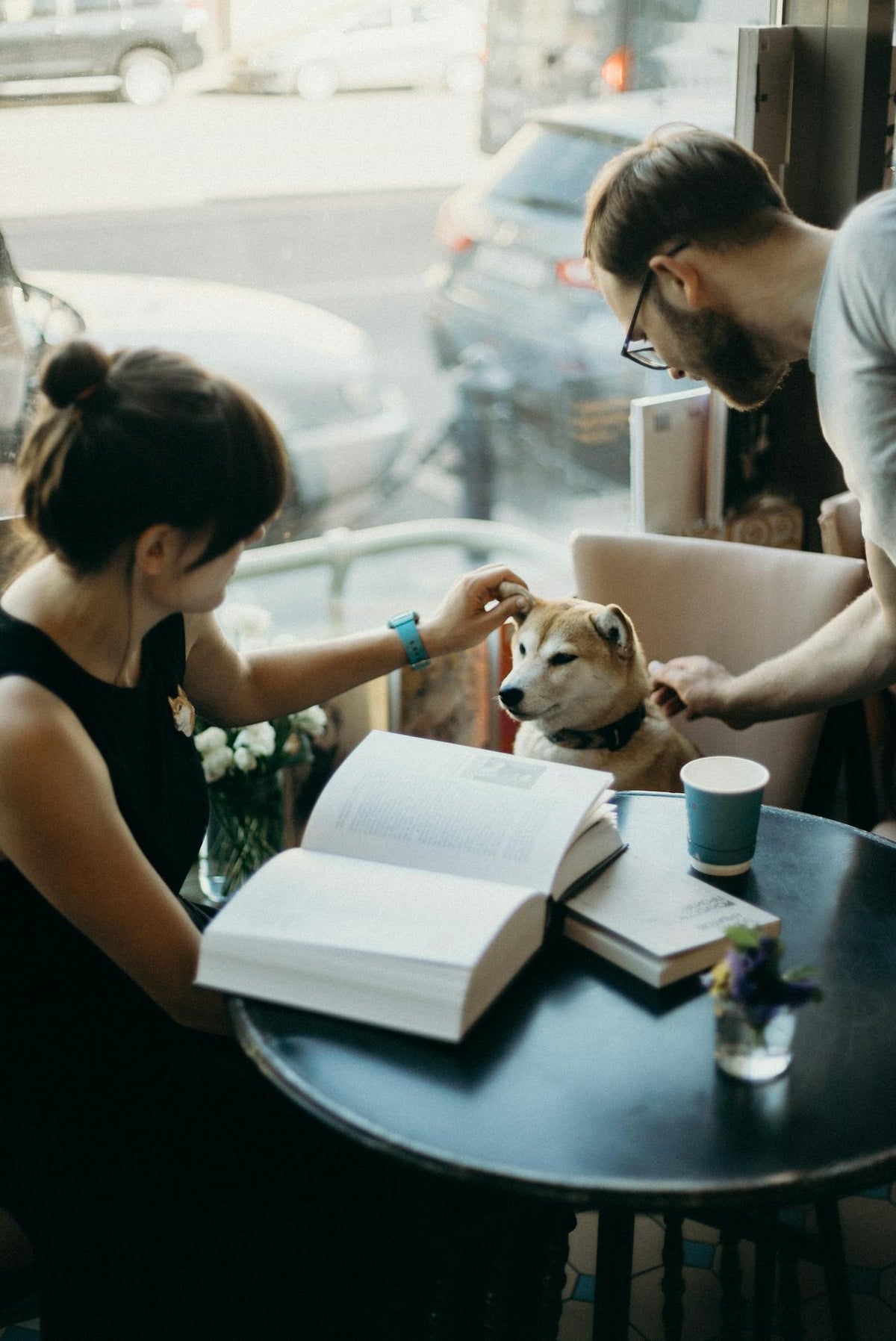 Eine Frau sitzt mit ihrem Hund im Café - ein Symbol dafür, dass Hunde uns überall begleiten.