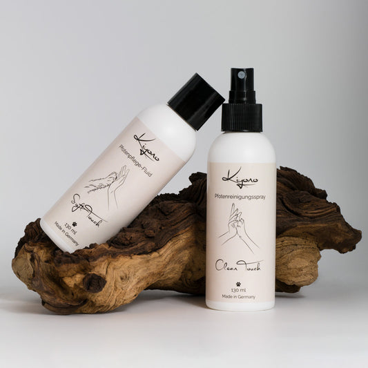 Ein Pfotenpflege-Set mit einem Pfotenreinigungsspray und einem Pfotenpflege-Fluid trapiert auf einer Wurzel